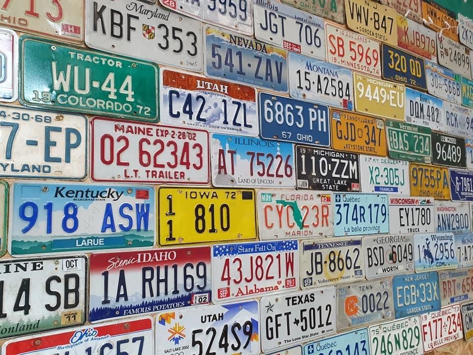 Mur recouvert d'une collection de plaques d'immatriculation provenant de différents États et régions.