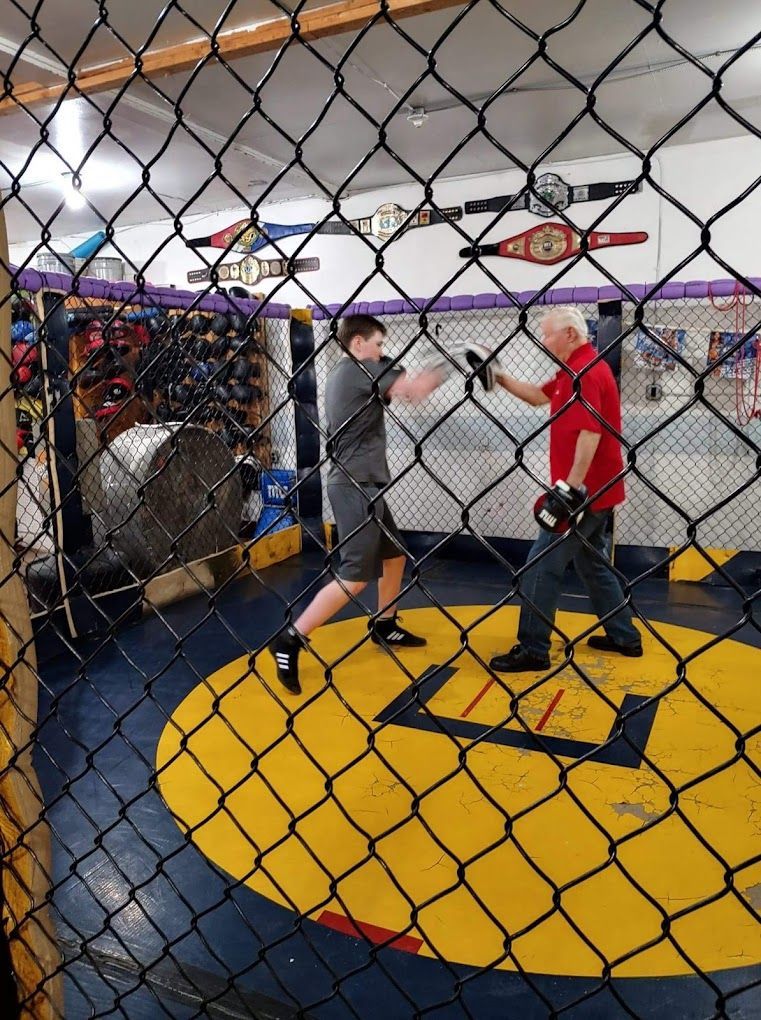 A man in a red shirt is boxing in a cage