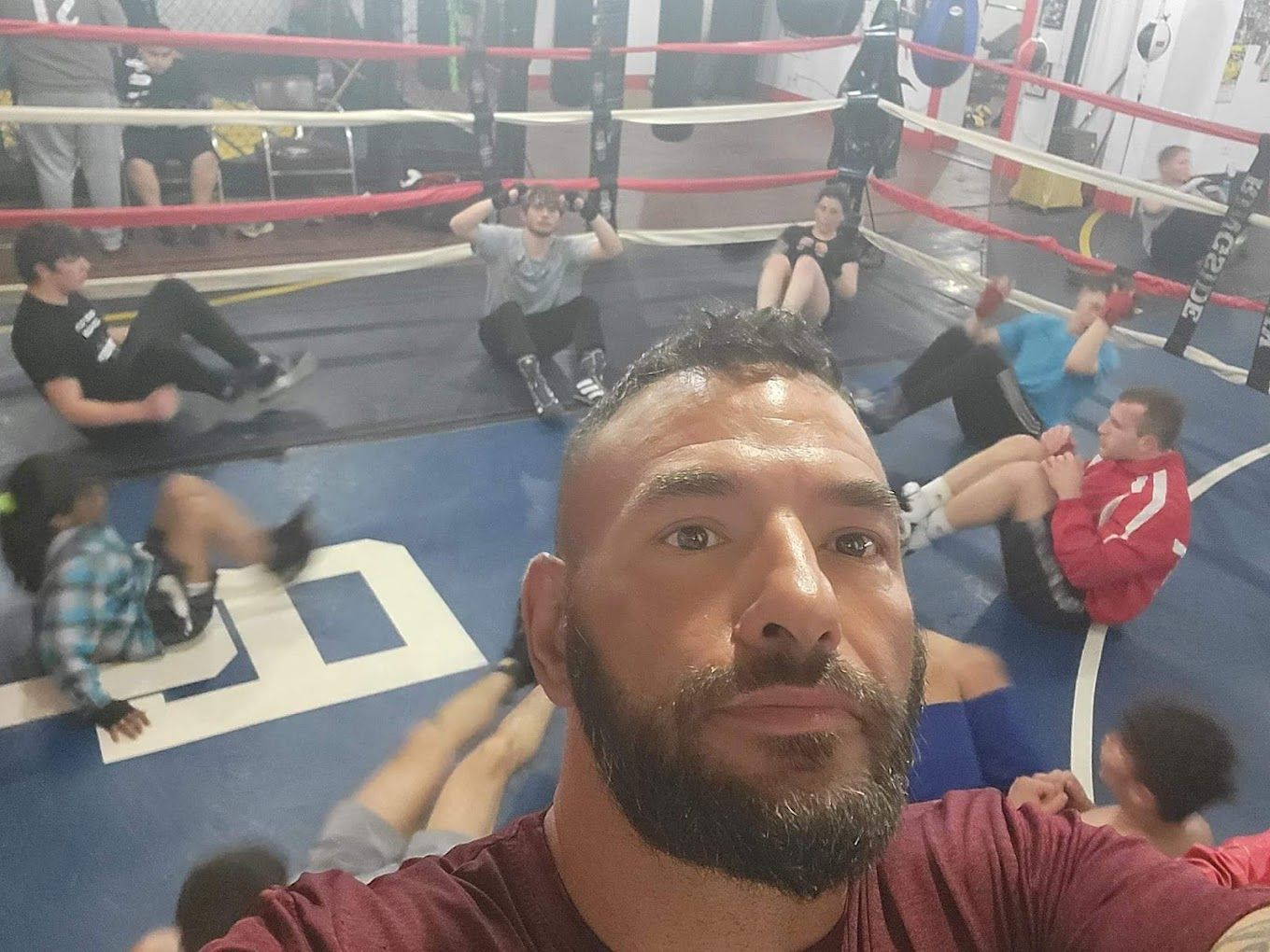 A man with a beard is taking a selfie in a boxing ring.