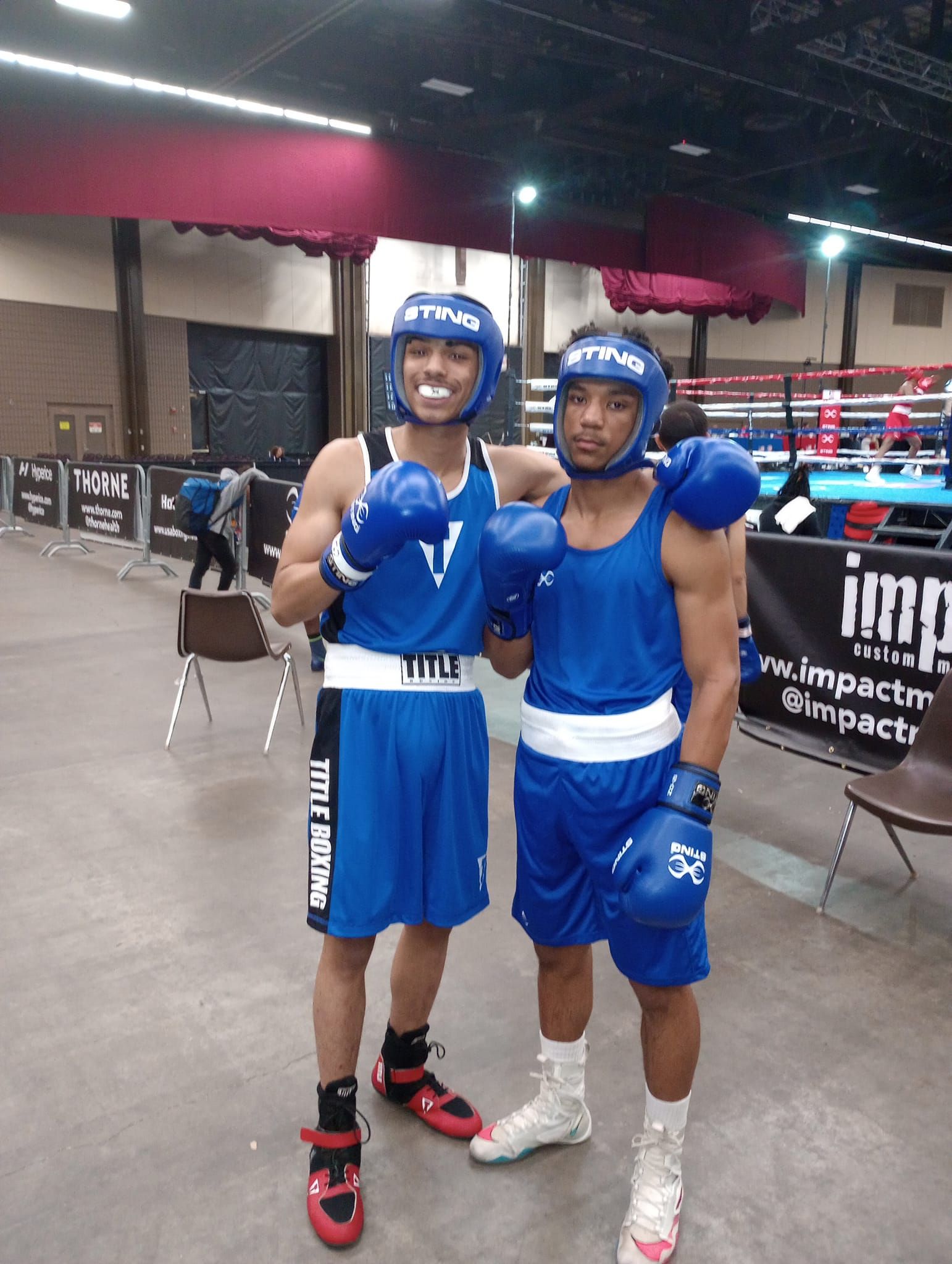 Two boxers are posing for a picture in front of a sign that says impact