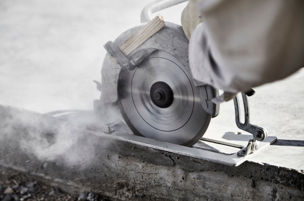 Person Using a Circular Saw to Cut Concrete, Creating Dust — Coastcut Concrete Cutting Pty Ltd in Port Stephens, NSW