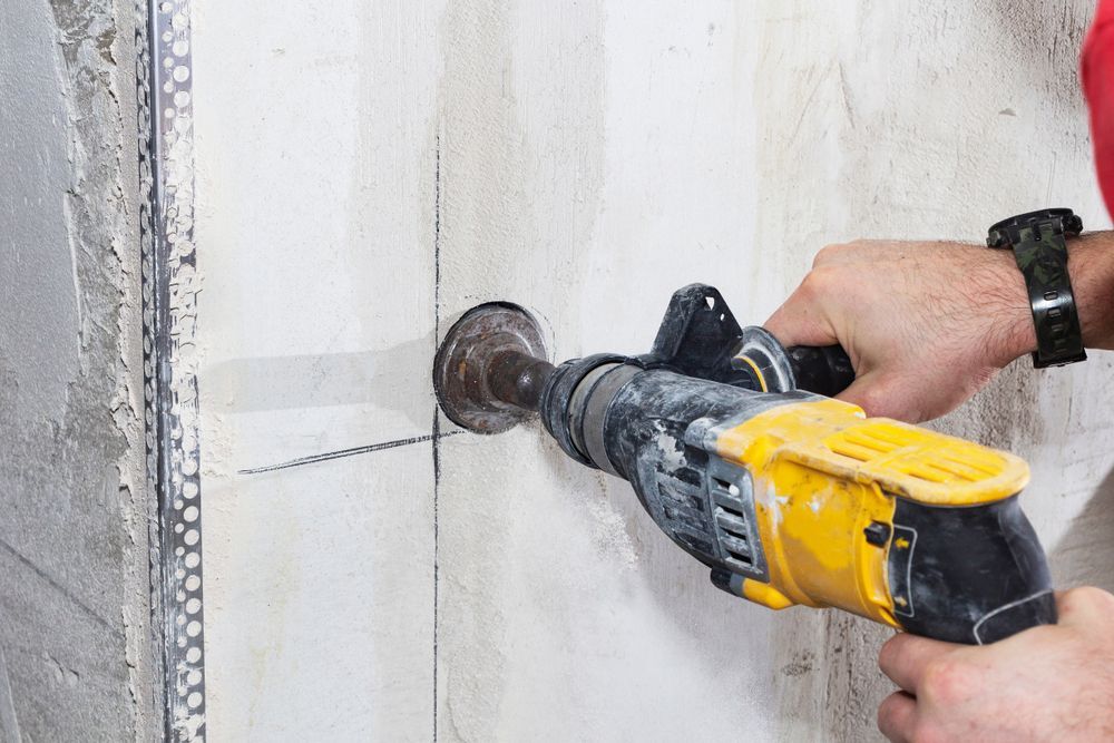 Person Drills a Hole in a Light-colored Wall  — Coastcut Concrete Cutting Pty Ltd in Port Stephens, NSW