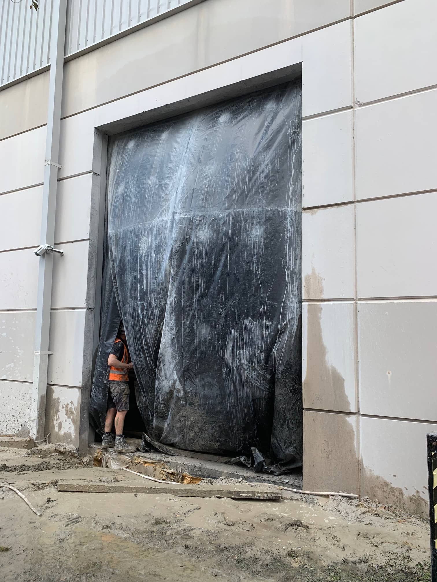 Man Standing in Front of a Black Tarp Covering a Large Doorway  — Coastcut Concrete Cutting Pty Ltd in Port Stephens, NSW