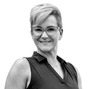 Robin with blonde pixie cut, glasses, and a sleeveless top, smiling at the camera.