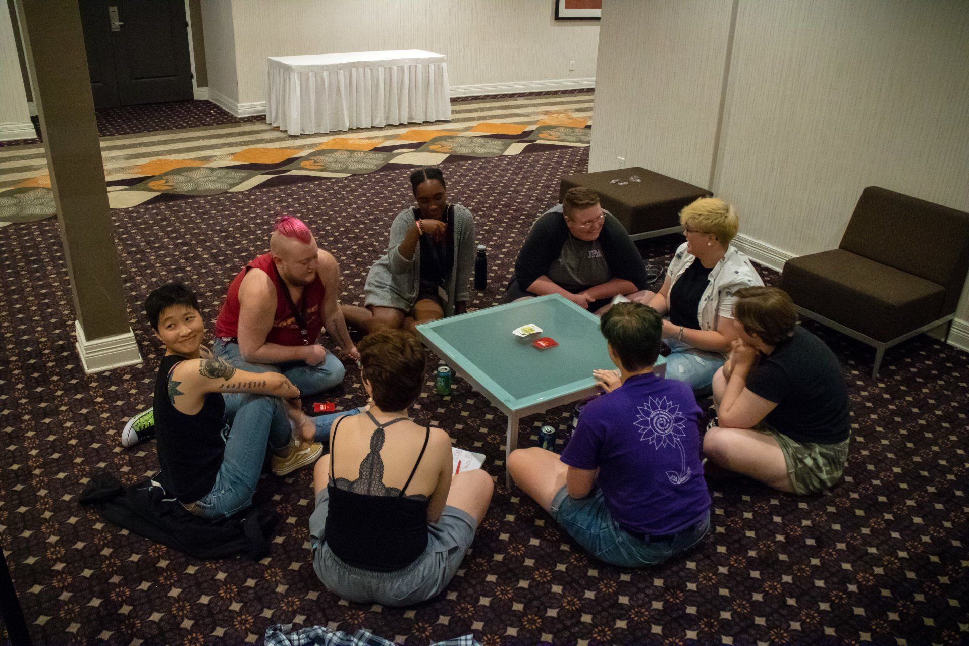 A large group of people siting on the floor around a coffee table, playing a game.