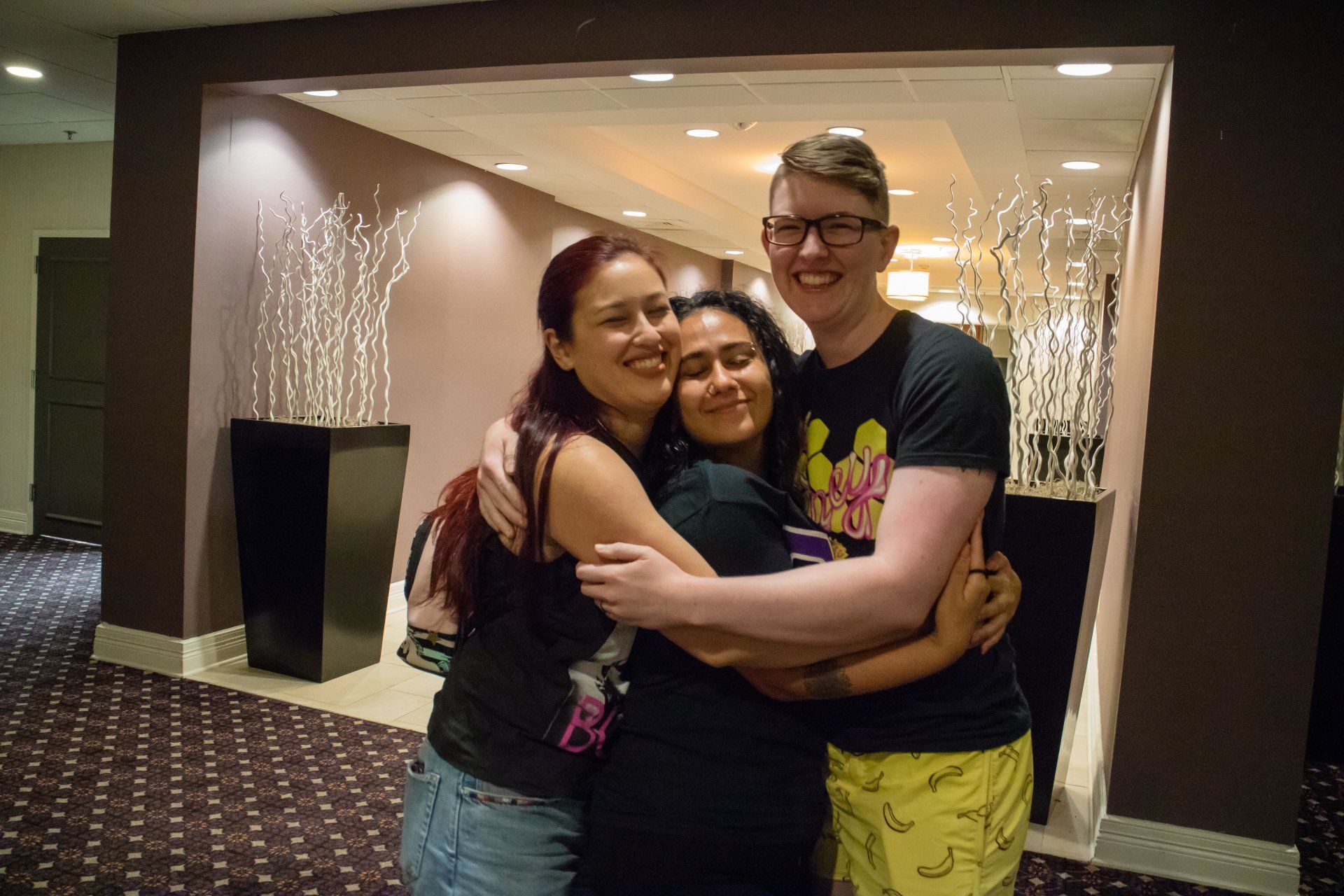 Three people posing together in a big hug