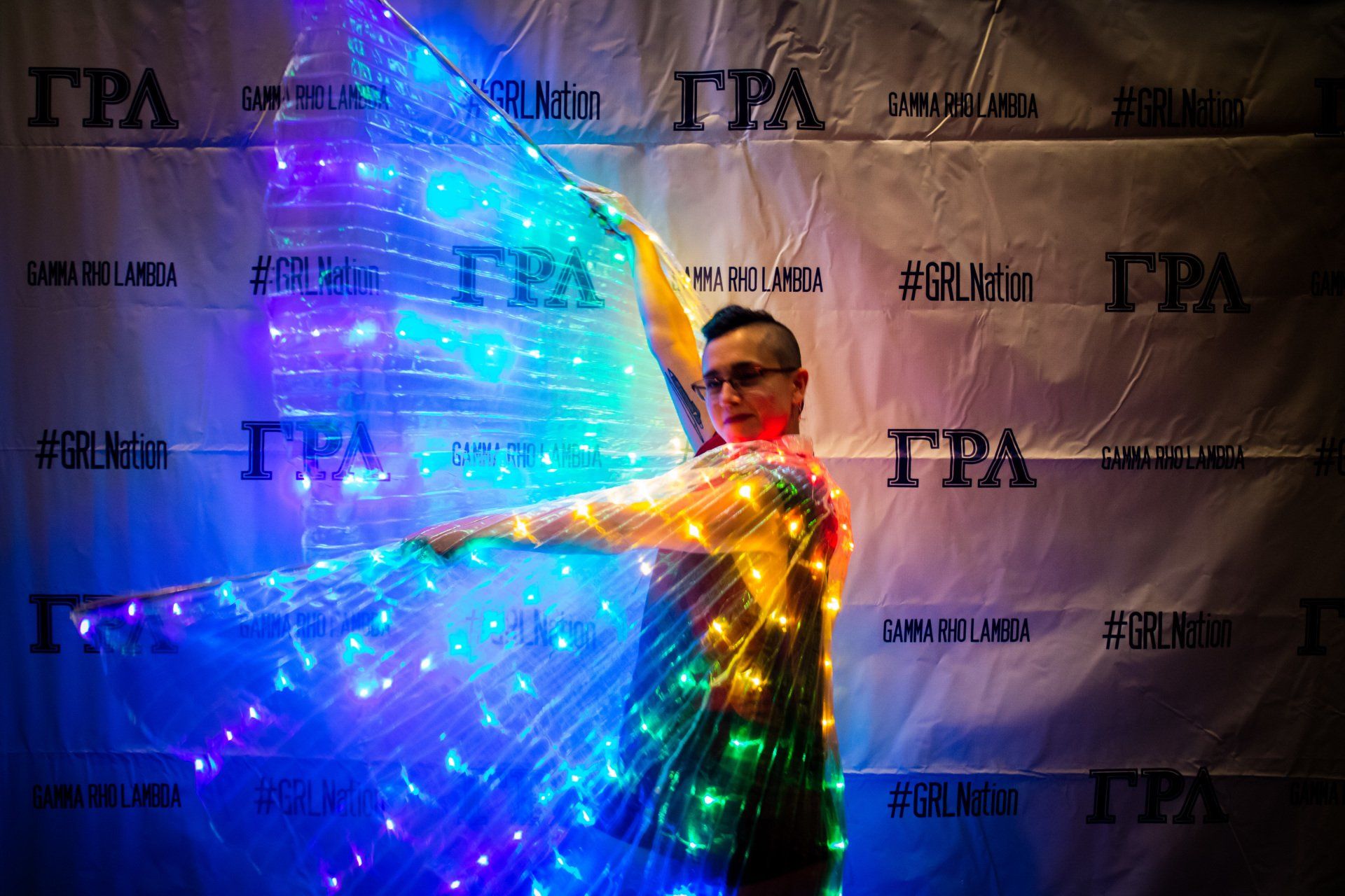 A person in a light up rainbow cape poses