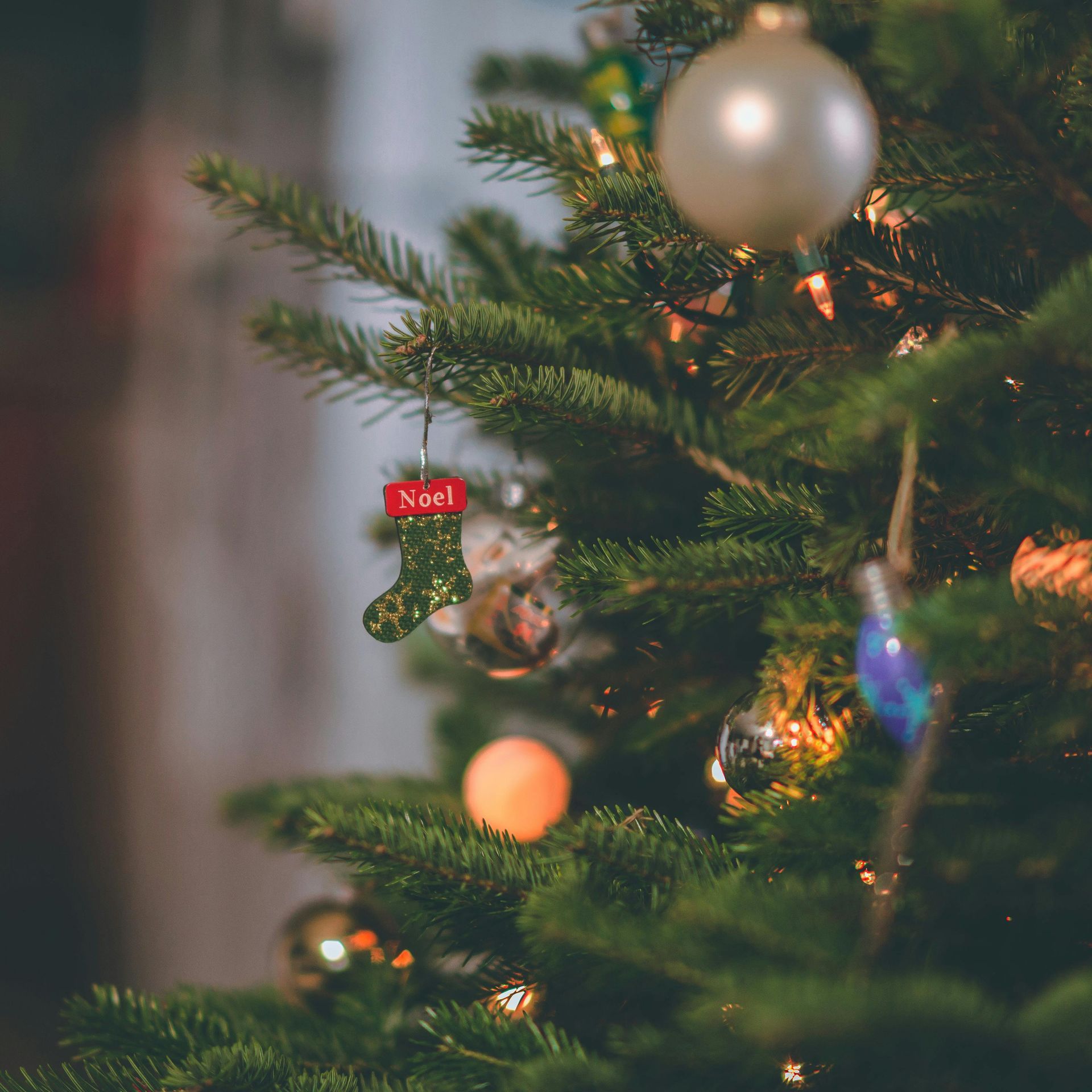 Christmas tree decorated with ornaments and lights, including a stocking that reads 