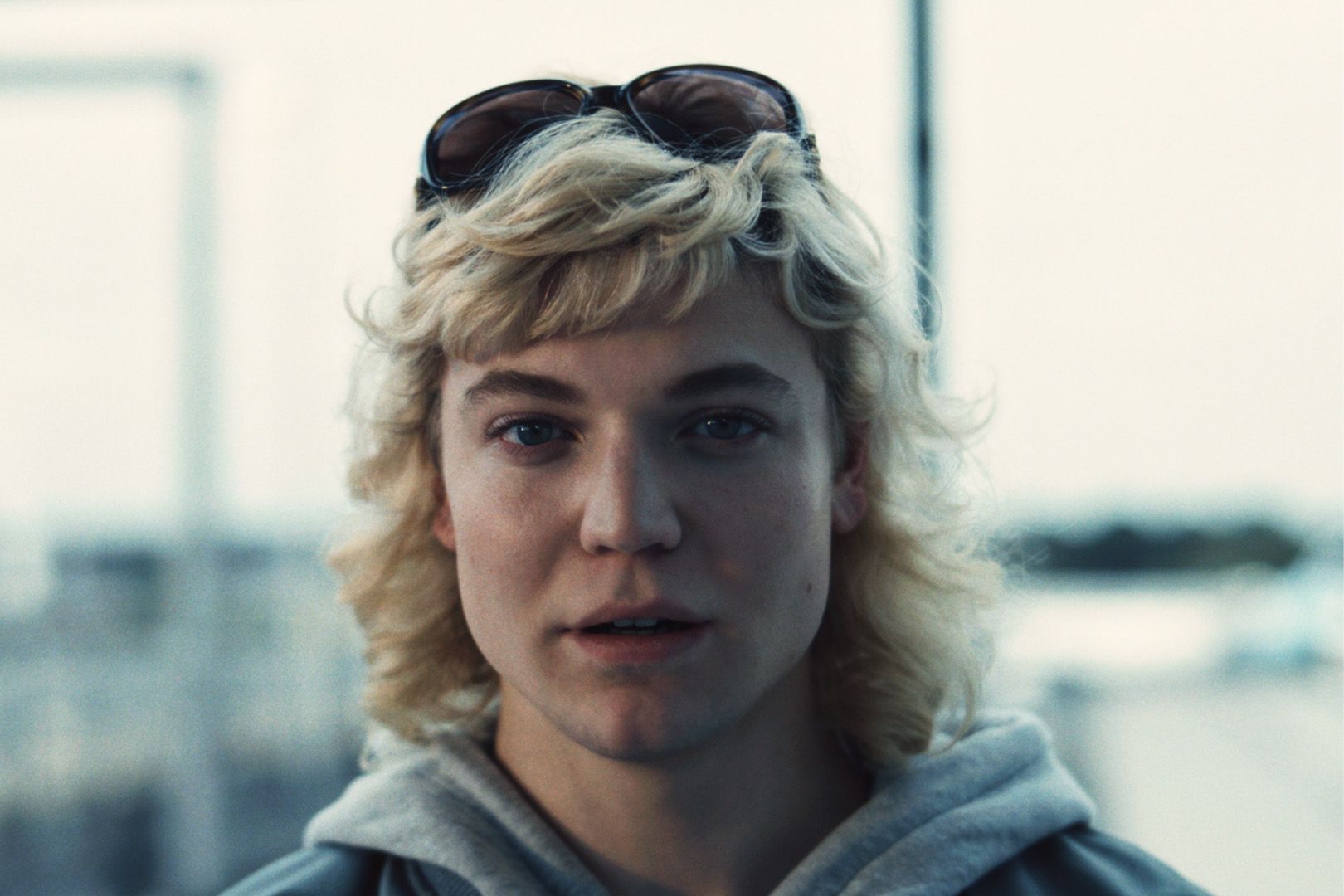 Eine Person mit Sonnenbrille und Kapuzenpullover blickt in die Kamera