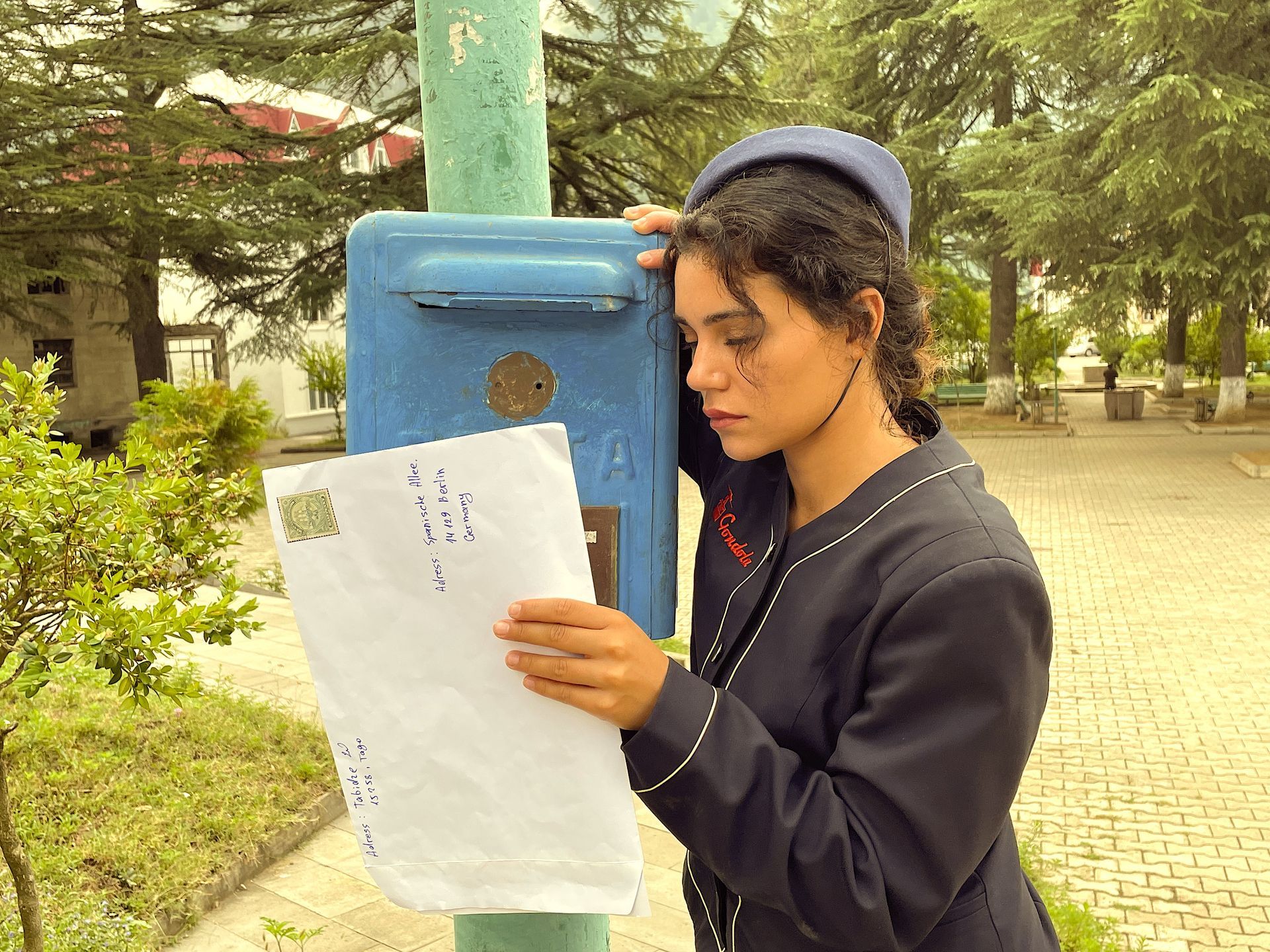 Eine Frau, die auf ein Stück Papier neben einem Briefkasten schaut