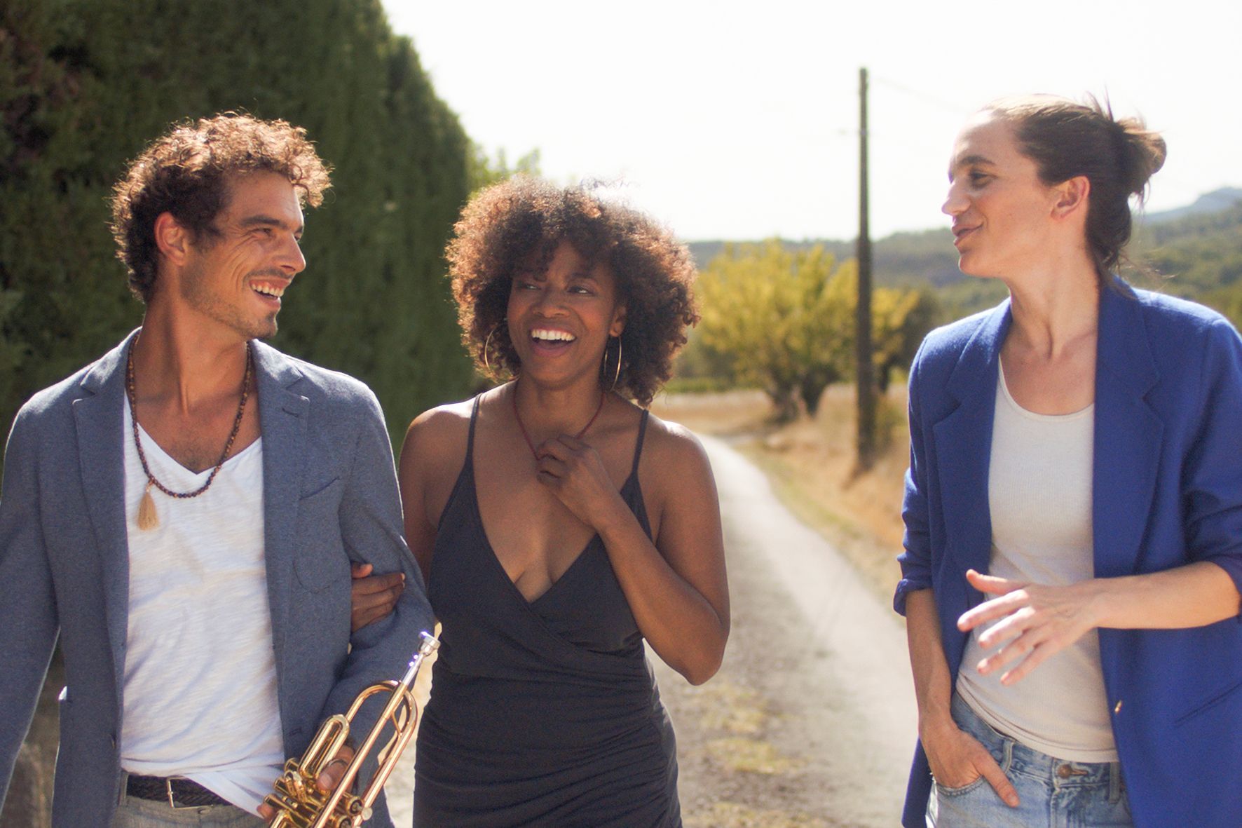 Ein Mann mit einer Trompete geht mit zwei Frauen