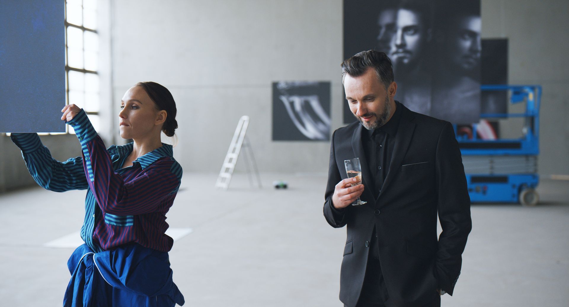 Ein Mann im Anzug steht neben einer Frau in einem blauen Kleid in einem Atellier
