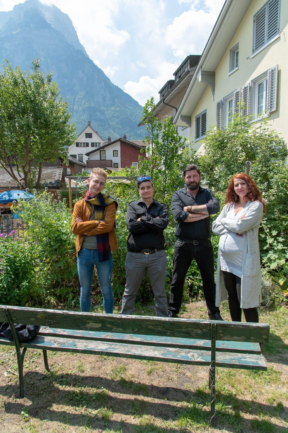 Eine Gruppe von Menschen steht neben einer Bank mit Bergen im Hintergrund