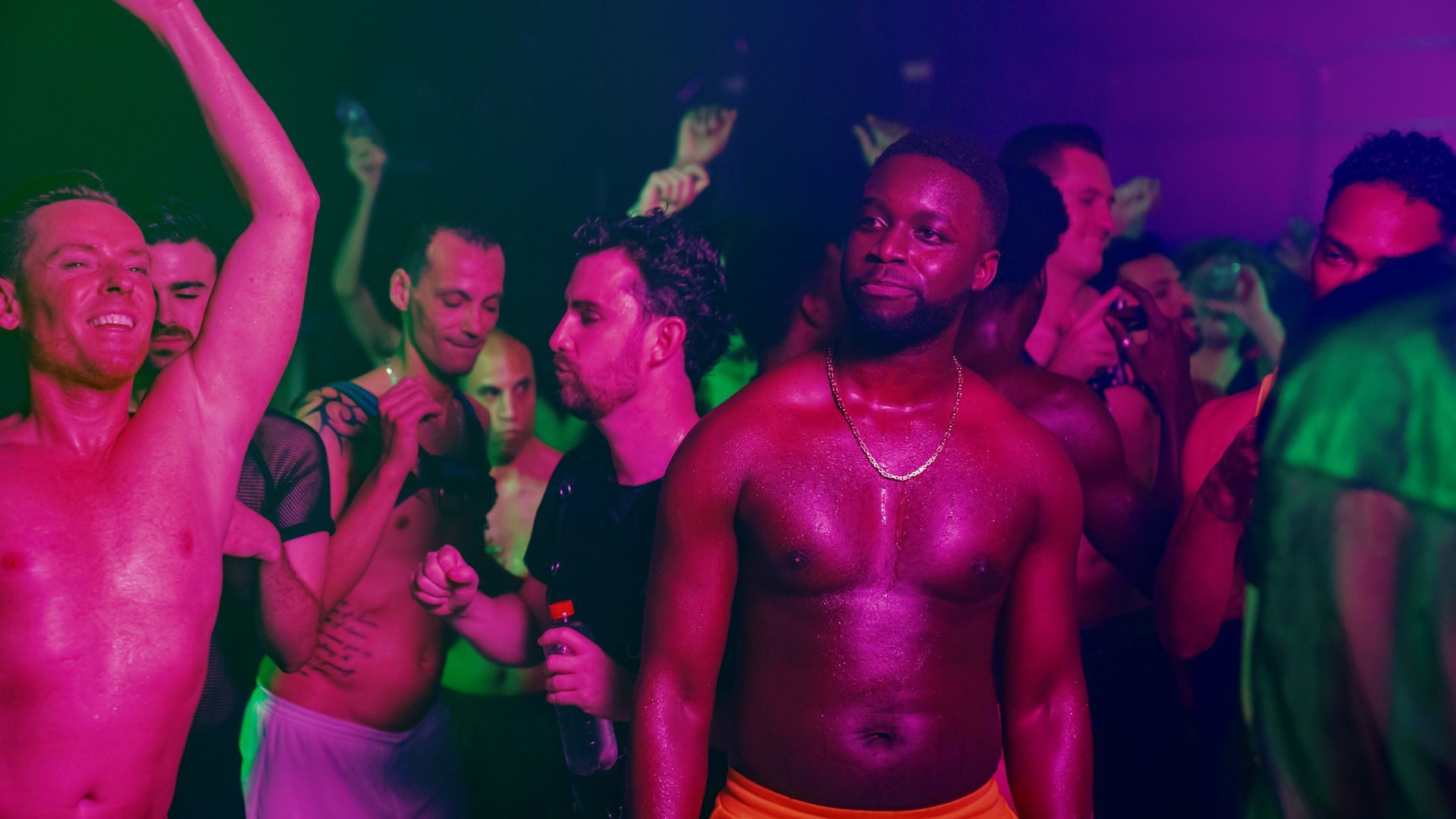 Ein Mann ohne Hemd steht in einer Menschenmenge auf einer Party