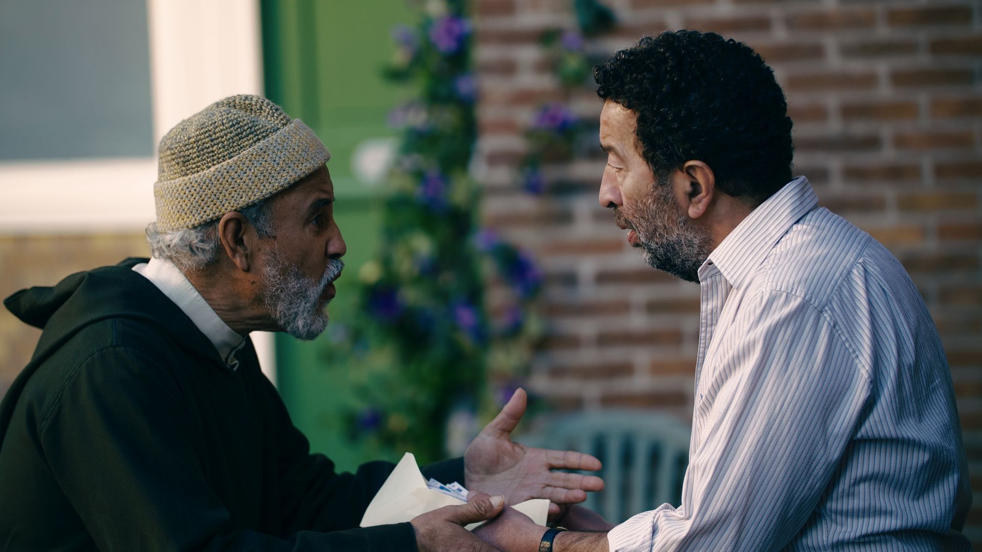 Zwei Männer unterhalten sich vor einem Backsteingebäude