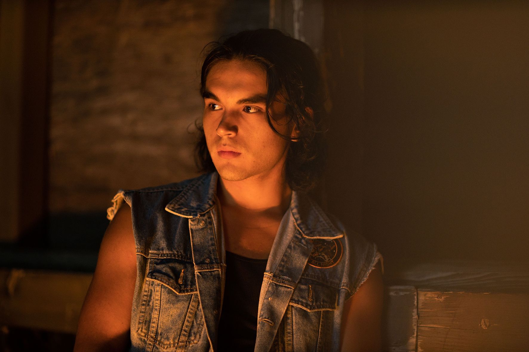 Ein junger Mann mit langen Haaren, der eine Jeansweste trägt