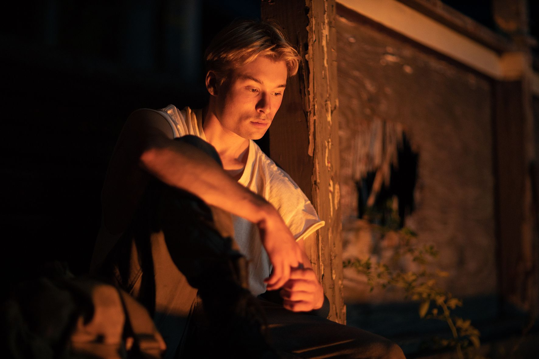 Ein Mann sitzt auf einer Veranda mit einem Feuer im Hintergrund