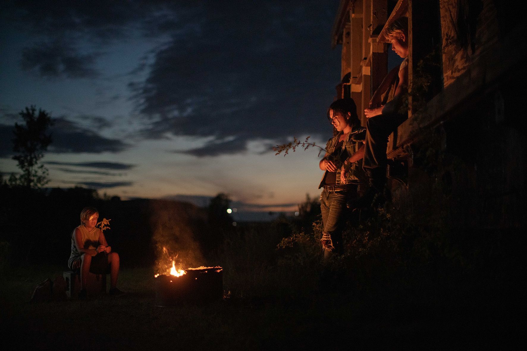 Eine Gruppe von Menschen sitzt nachts um ein Feuer herum
