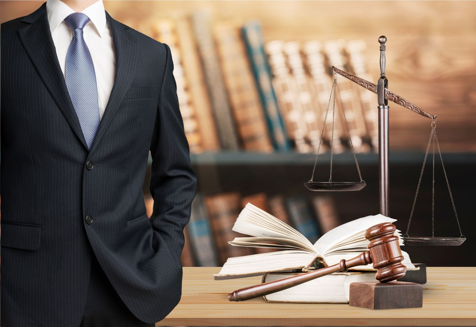 Man in suit with law books, gavel, and scales.