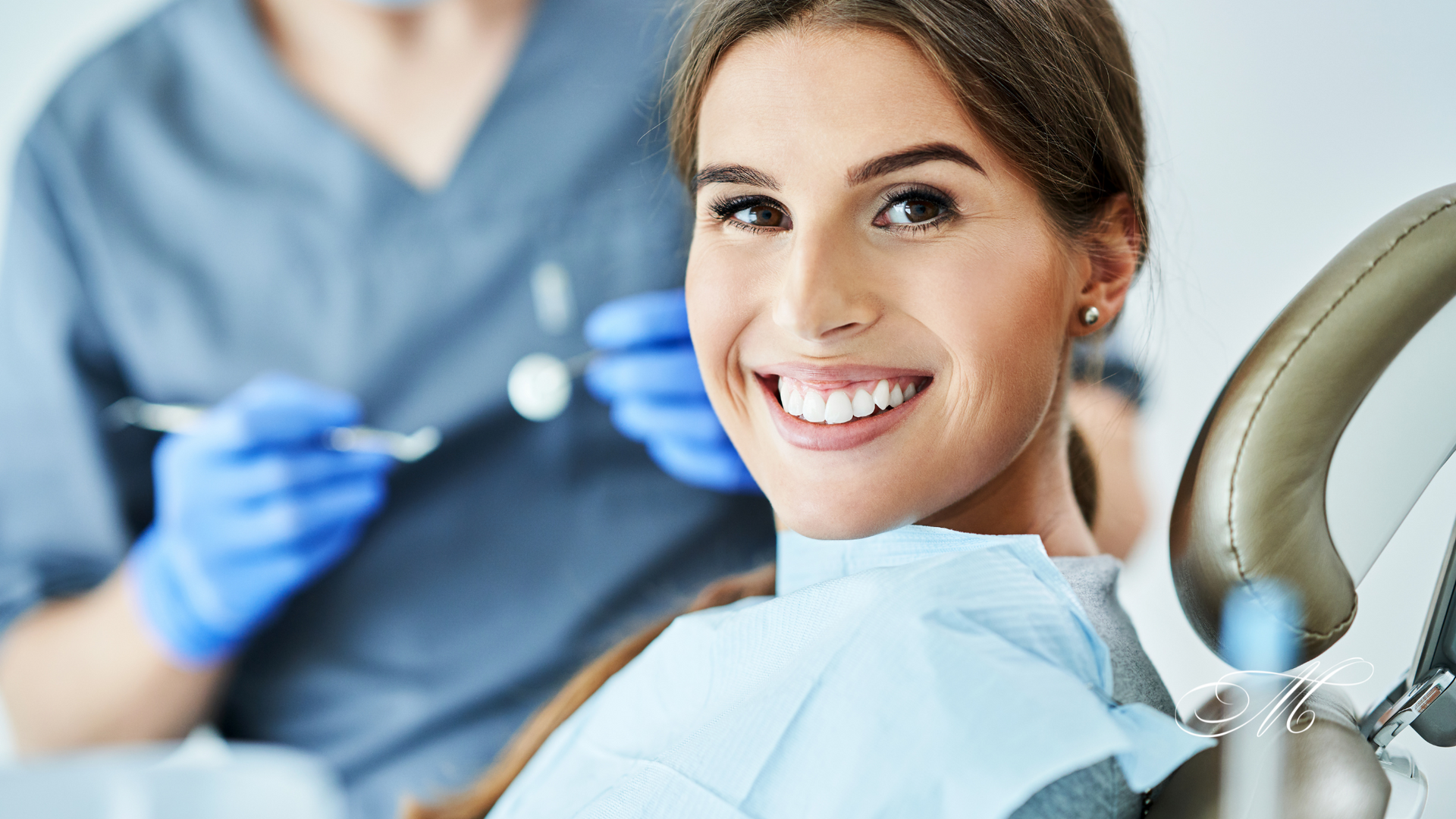 A woman is smiling while sitting in a dental chair.