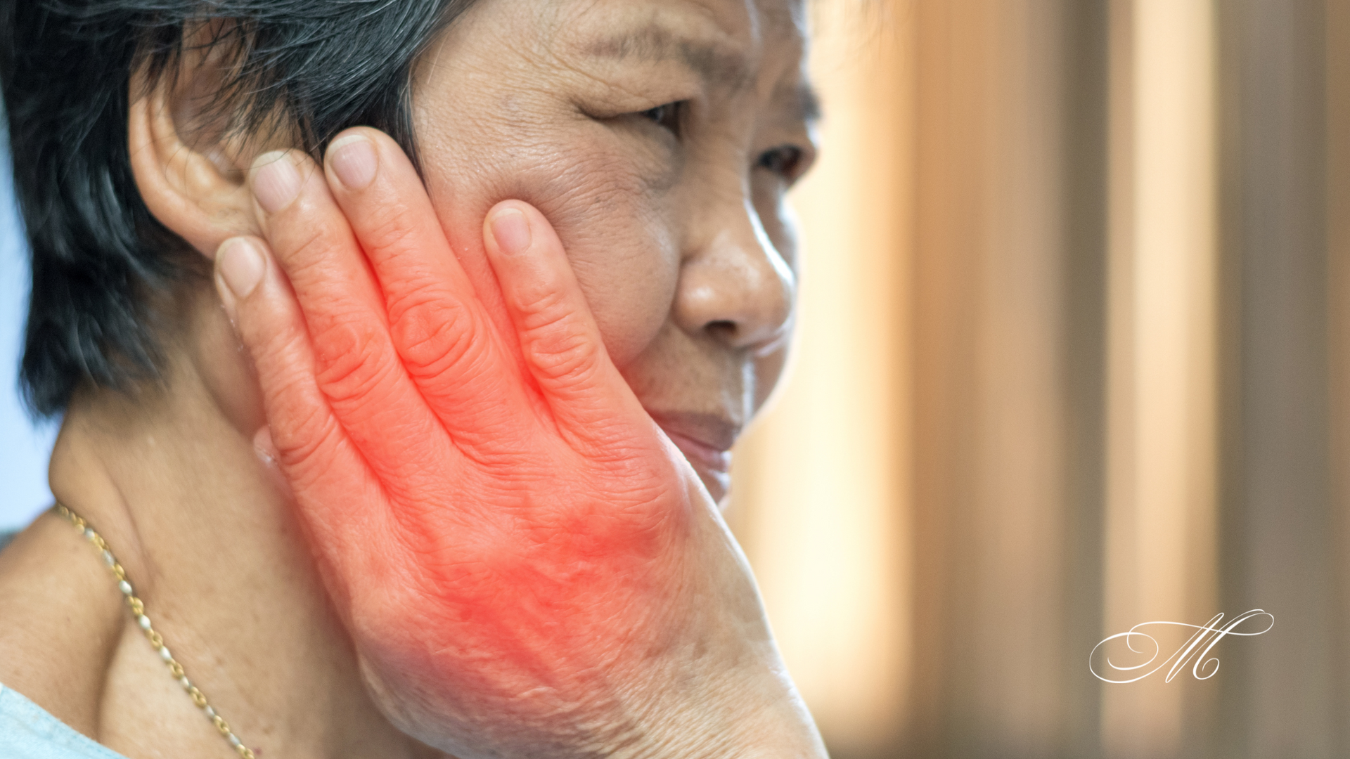 An elderly woman is holding her hand to her face because she has a toothache.