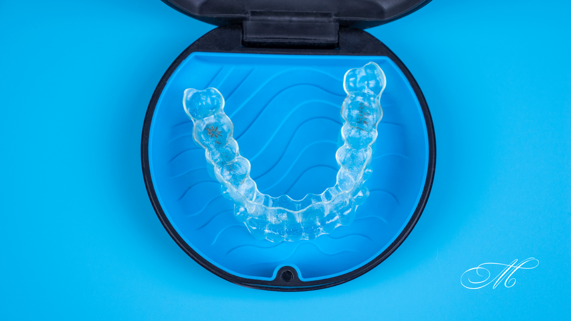 A pair of clear braces in a case on a blue surface.