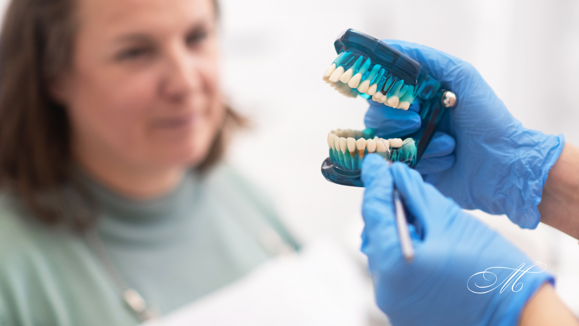 A dentist is holding a model of a person 's teeth in front of a woman.