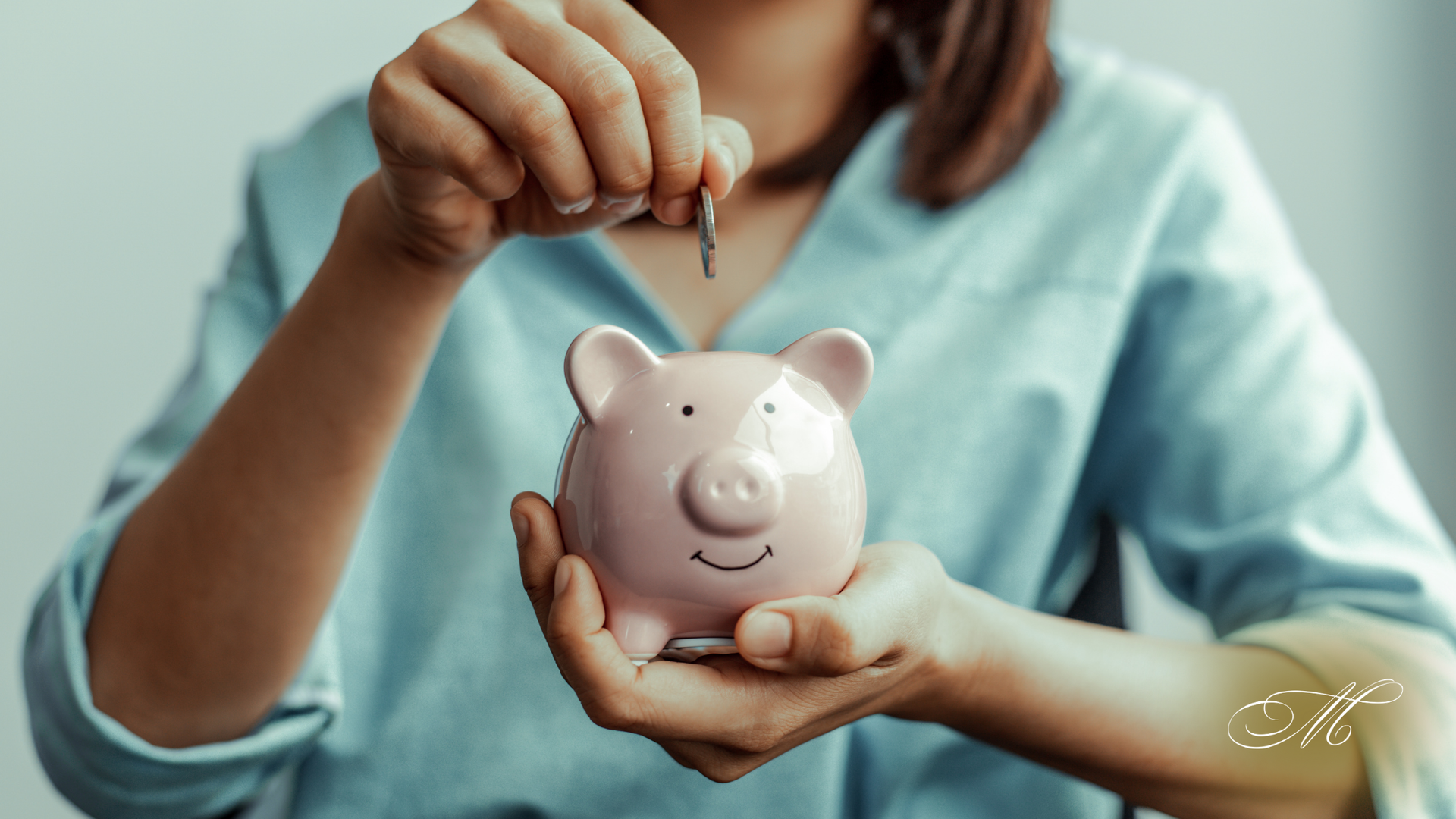 A woman is putting a coin into a piggy bank.