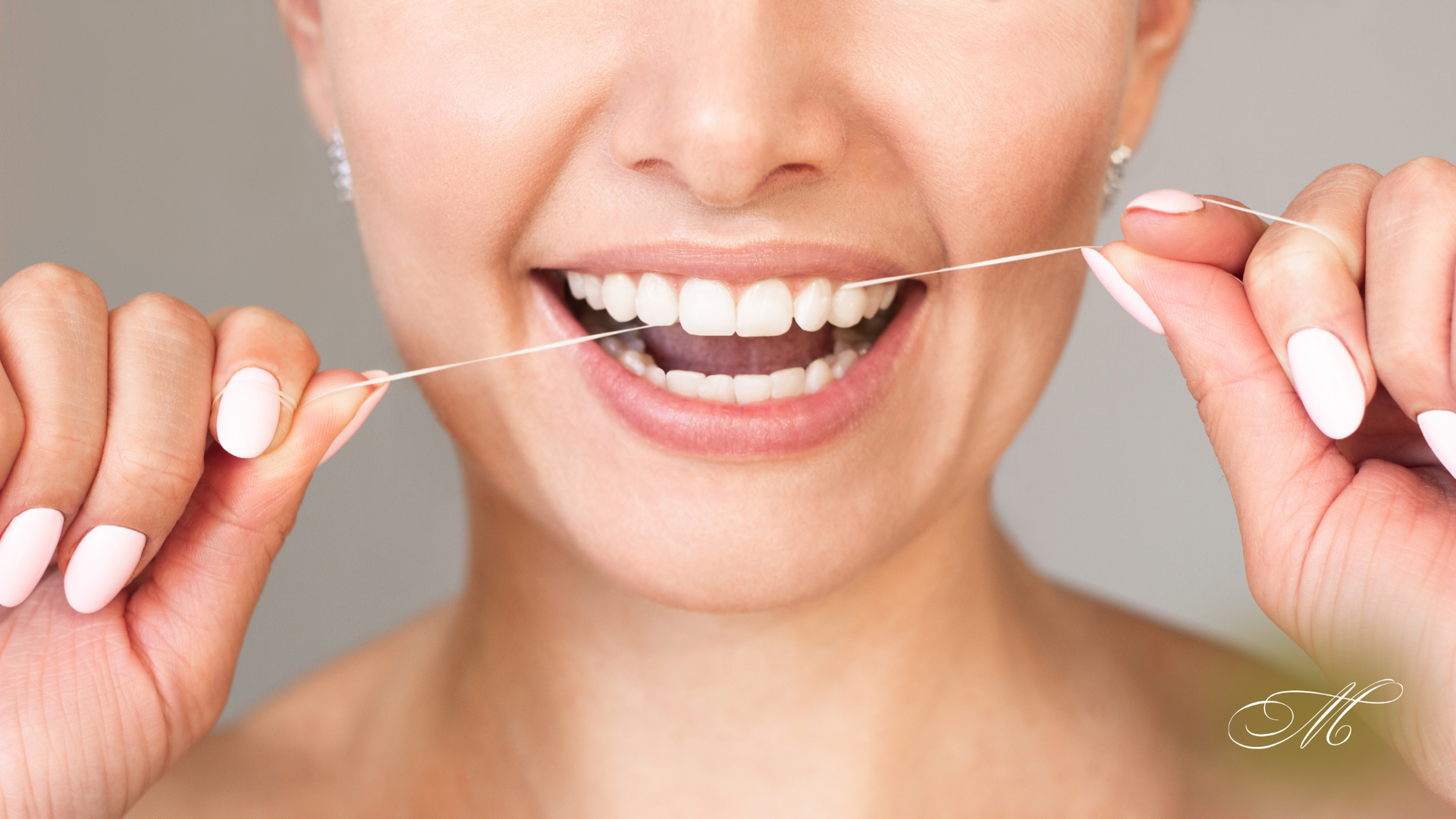 A woman is flossing her teeth with a dental floss.