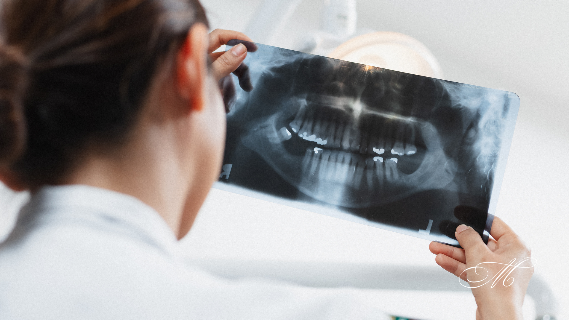 A dentist is looking at an x-ray of a patient 's teeth.