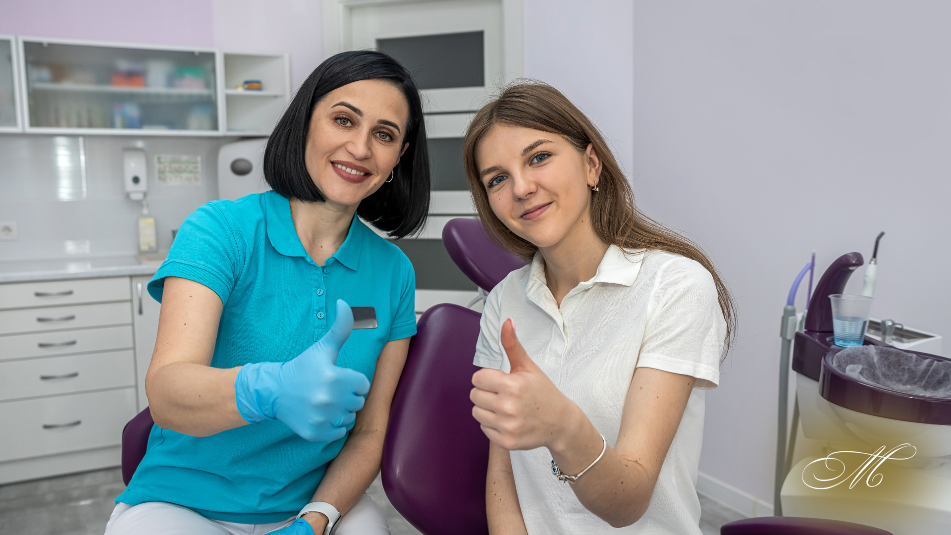 A dentist and patient in a dental office giving thumbs up.