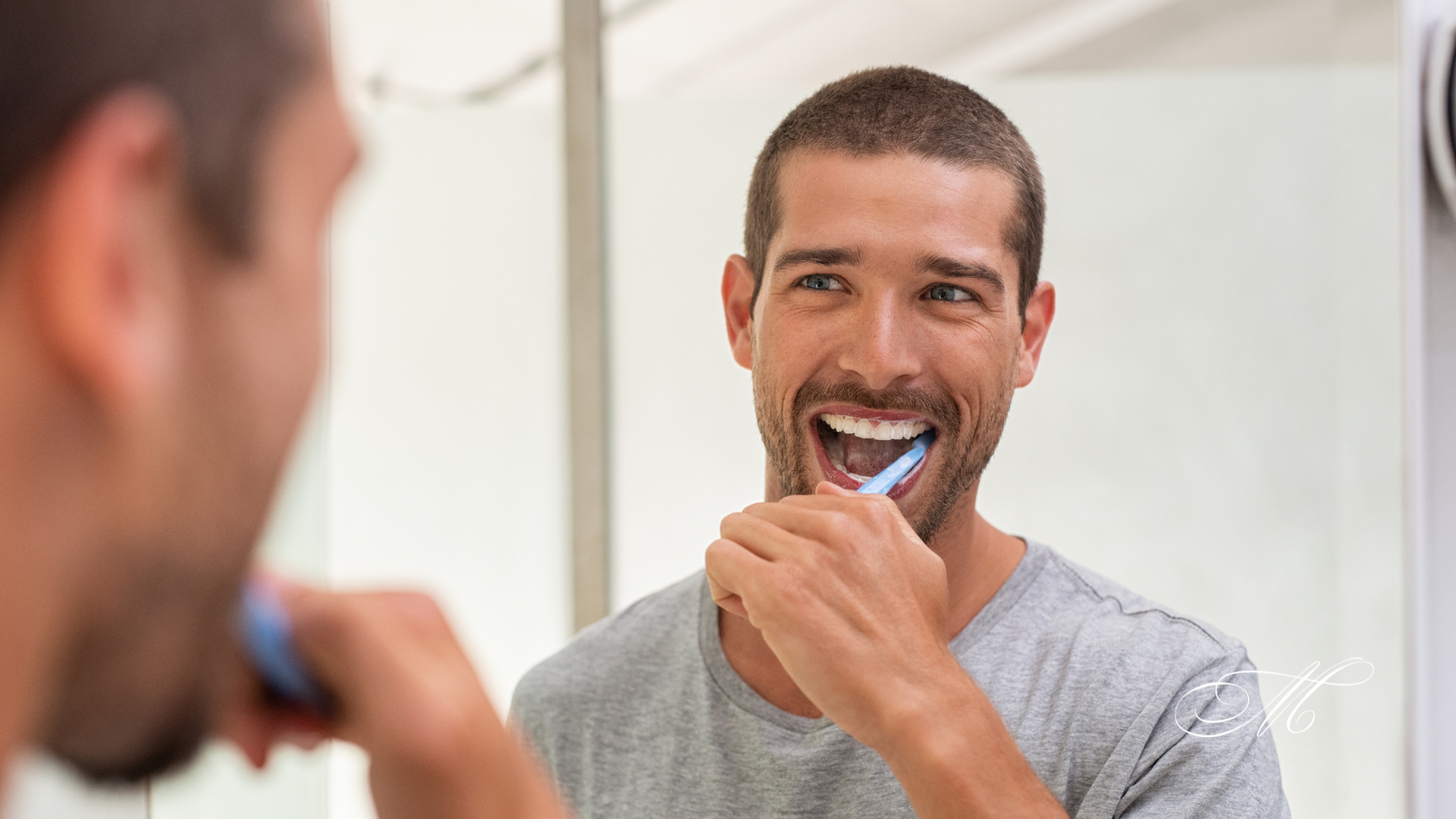 A man is brushing his teeth in front of a mirror.