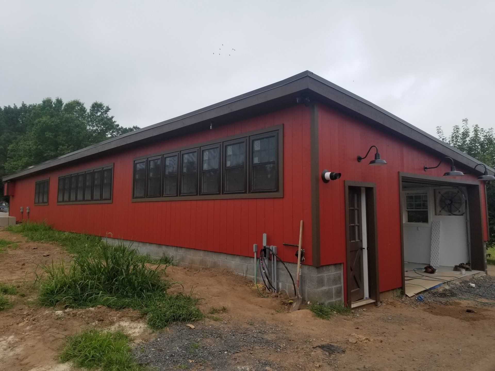 Red building with brown trim and windows, a garage, and an open door.
