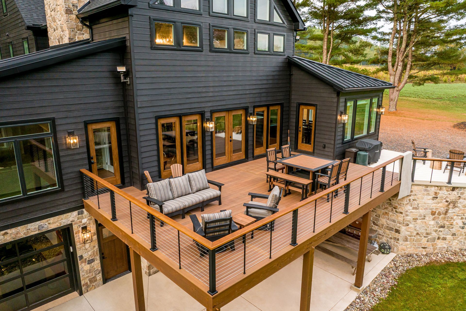 Modern house with a large deck, charcoal exterior, brown deck, and outdoor furniture.