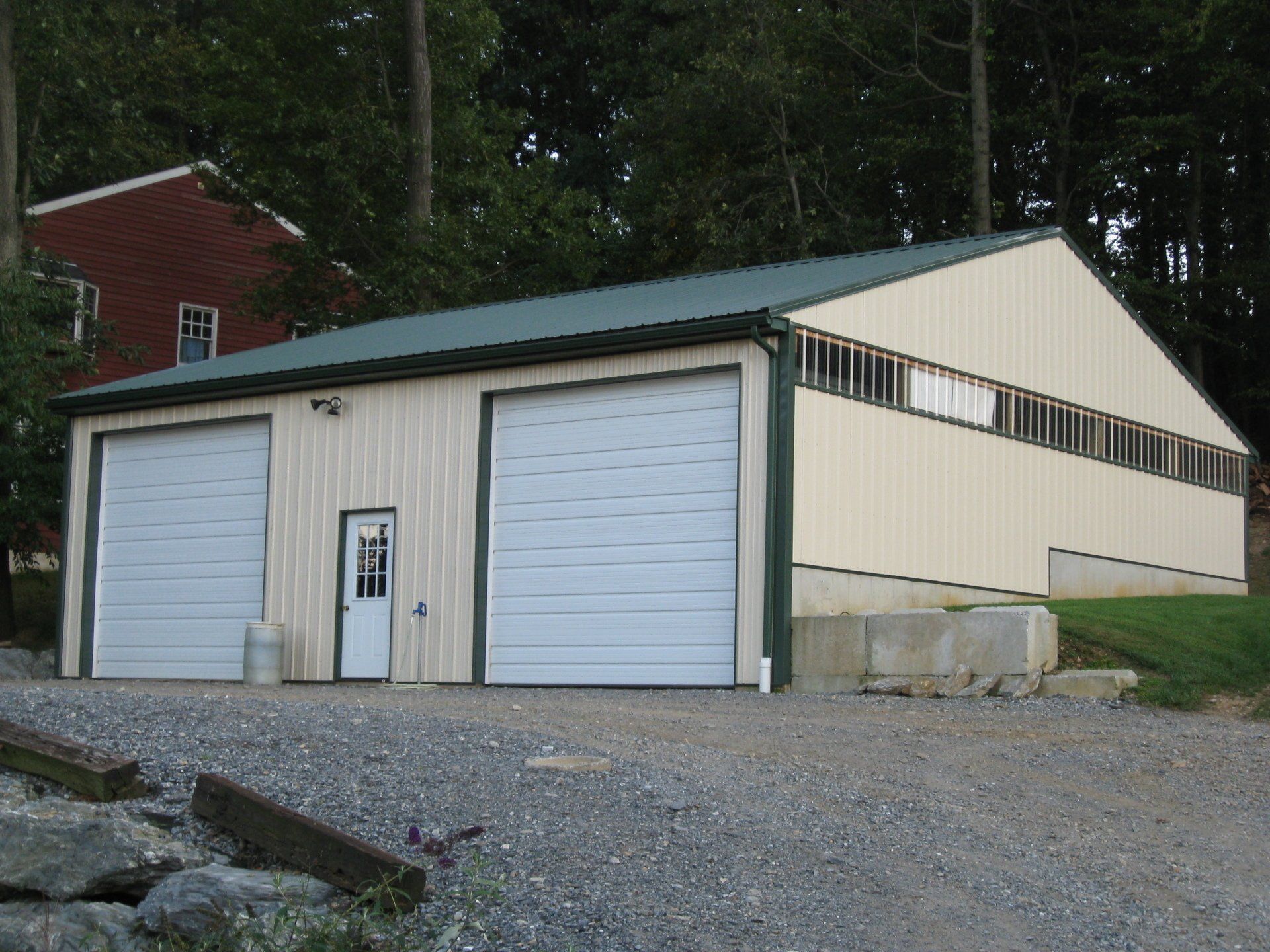 Tan metal garage with two doors, a side door, and a green roof.