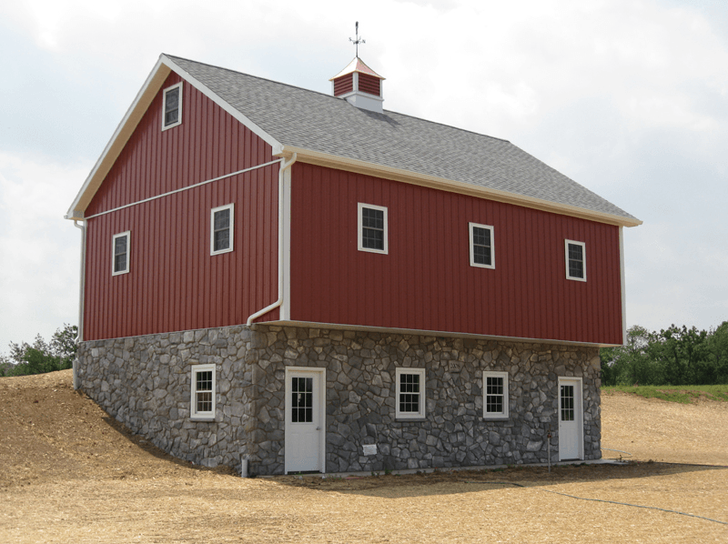 Red barn with stone foundation; windows and white trim.