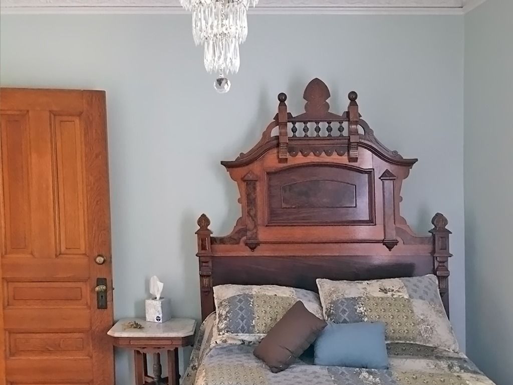 Bedroom with antique wooden bed frame, door, and a crystal chandelier.