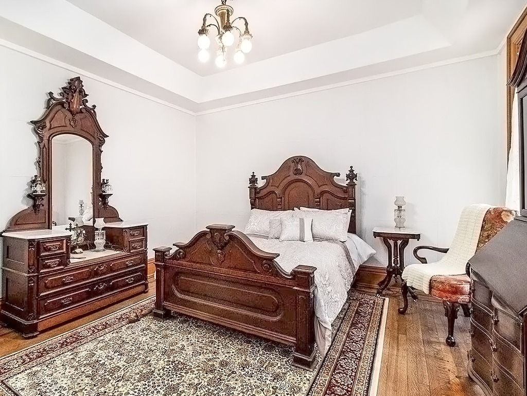 Ornate antique bedroom with wooden furniture and patterned rug.
