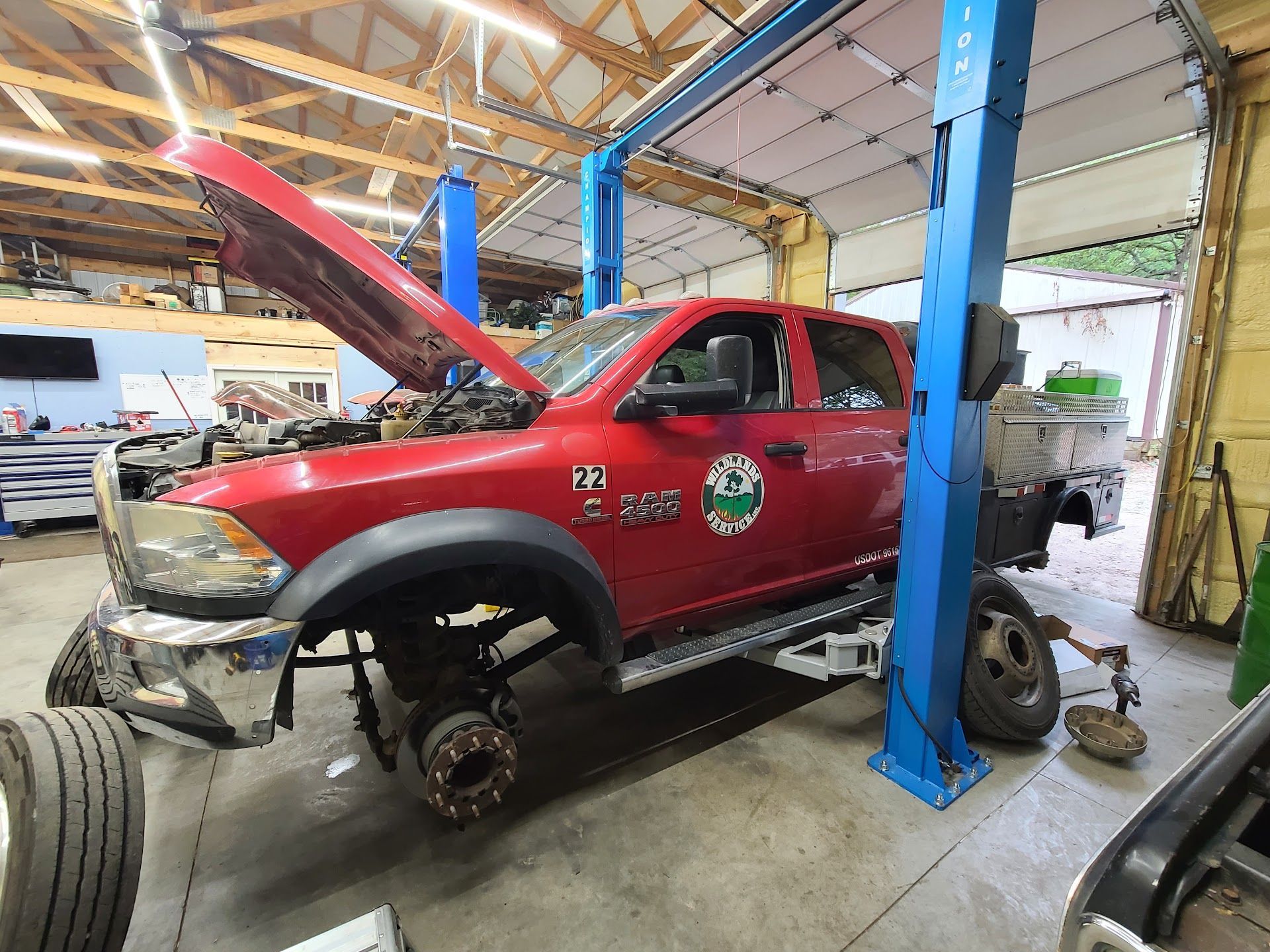 Red pickup truck on a lift in an auto repair shop with hood open and front wheel removed | C & C Automotive