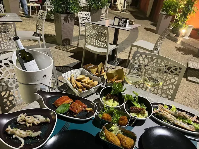 Tavolo da ristorante all'aperto con vari piatti e una bottiglia di vino in un secchiello del ghiaccio.