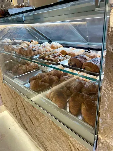 Pasticcini esposti in una vetrina di un panificio. File di croissant, paste danesi e altri prodotti da forno.