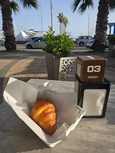 Croissant in un cestino sul tavolo di un bar, con vista sul porto sullo sfondo.