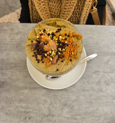 Coppa gelato in una ciotola di vetro su un piattino, guarnita con noci e gocce di cioccolato.