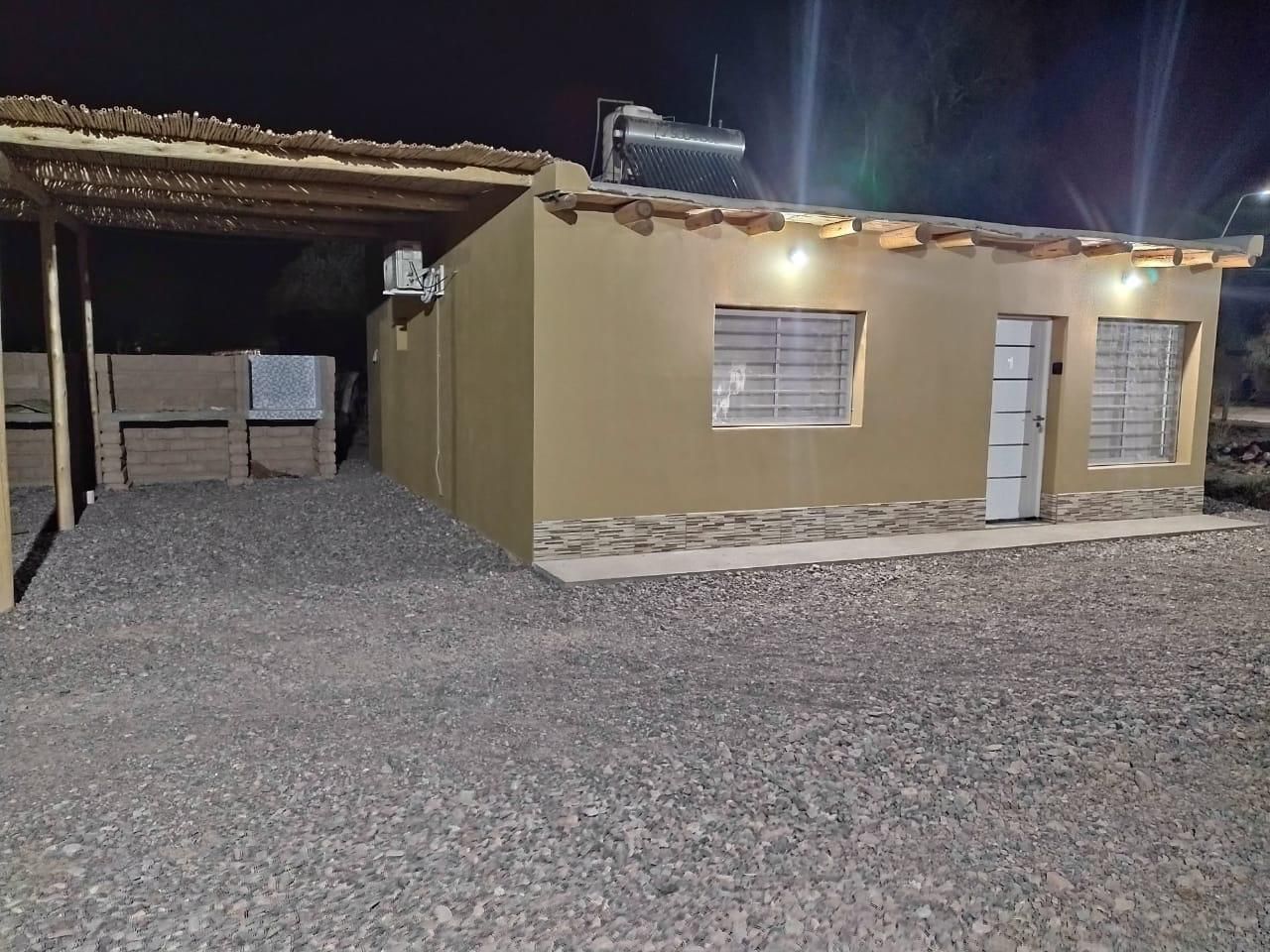 Cabaña color canela con entrada de grava. Porche cubierto, calentador de agua solar y dos ventanas.