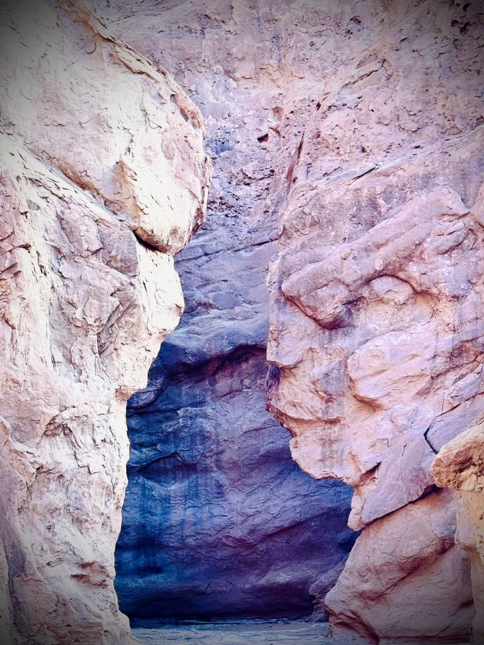 Las paredes del cañón con formaciones que se asemejan a rostros humanos enmarcan un cañón interior teñido de azul.