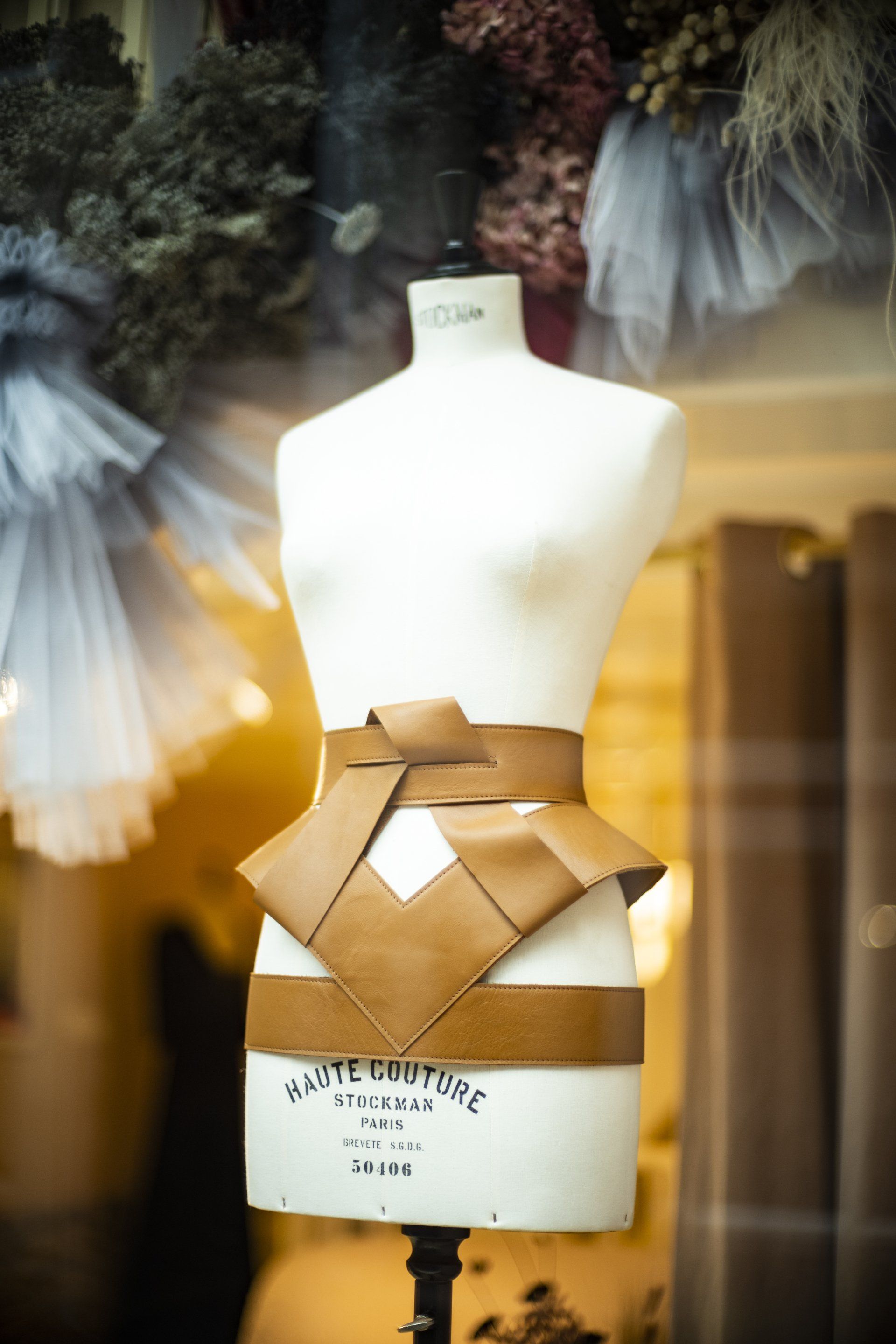 Paspop met bruine leren riem in etalage.