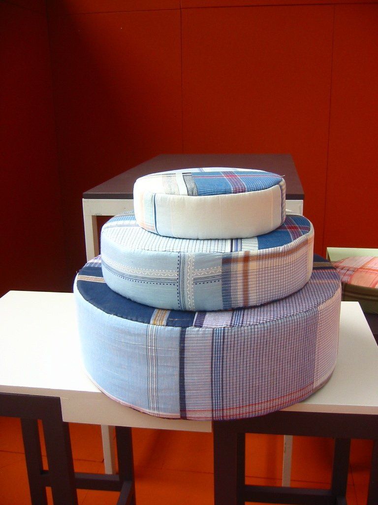 Drie op elkaar gestapelde ronde taart vormige kussens van blauw en wit gebloemde stoffen.