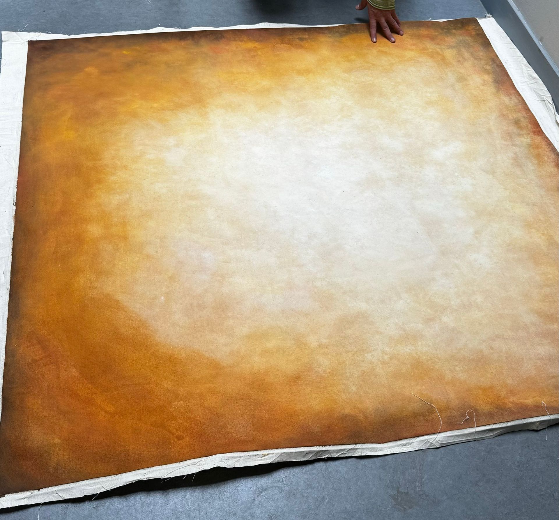 Bruin oranje backdrop gemeleerd op een groot vierkant doek, vastgehouden door handen.