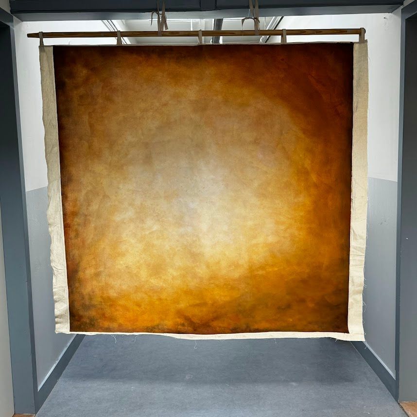 Bruin en oranje achtergrond hangt in een gang. De achtergrond heeft een verloop met een licht centrum.