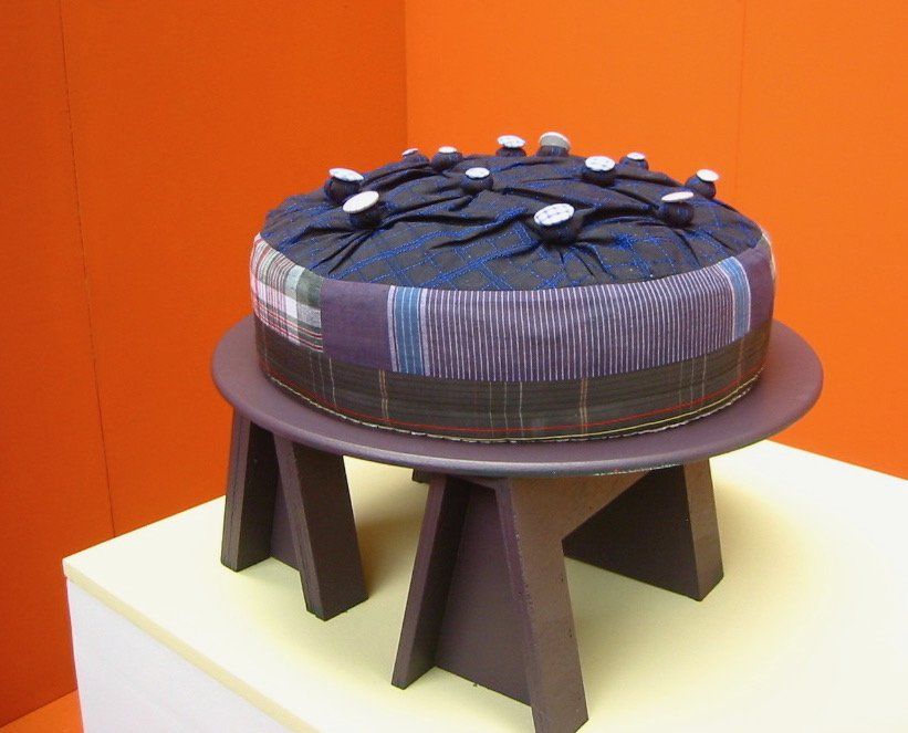 Rond textielkunstwerk taart op een paarse tafel met een feloranje achtergrond.